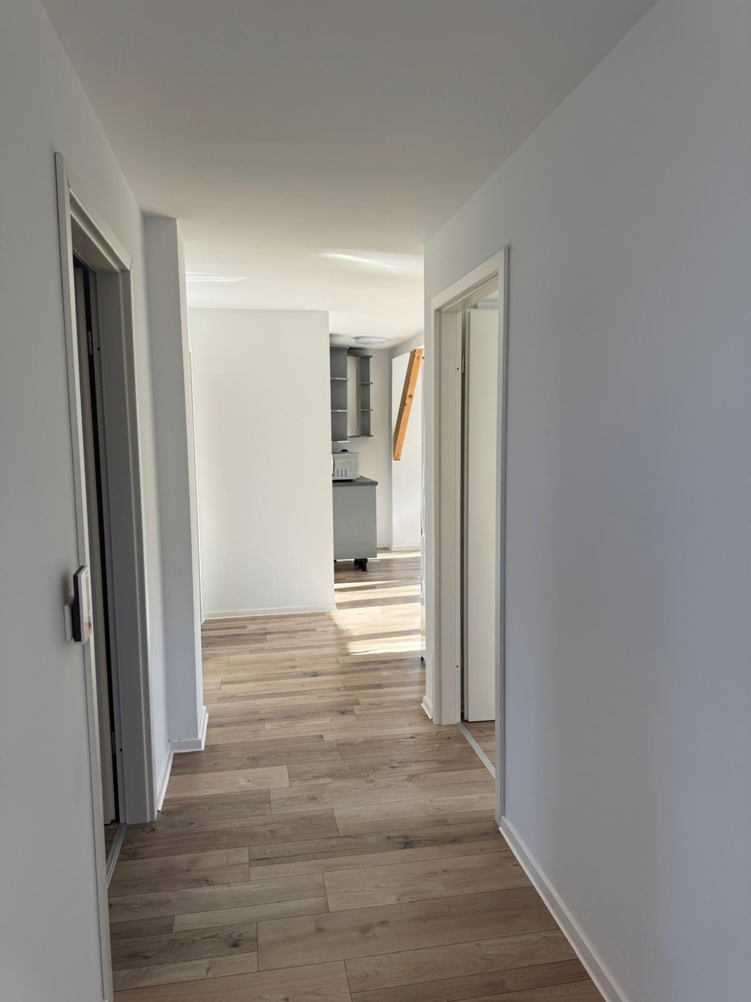 Heller Flur mit Holzboden und Blick in die Küche
