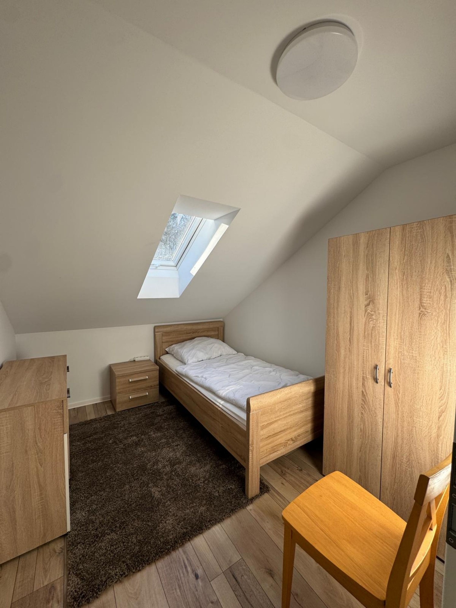 Schlafzimmer mit Einzelbett, Kleiderschrank und Dachfenster